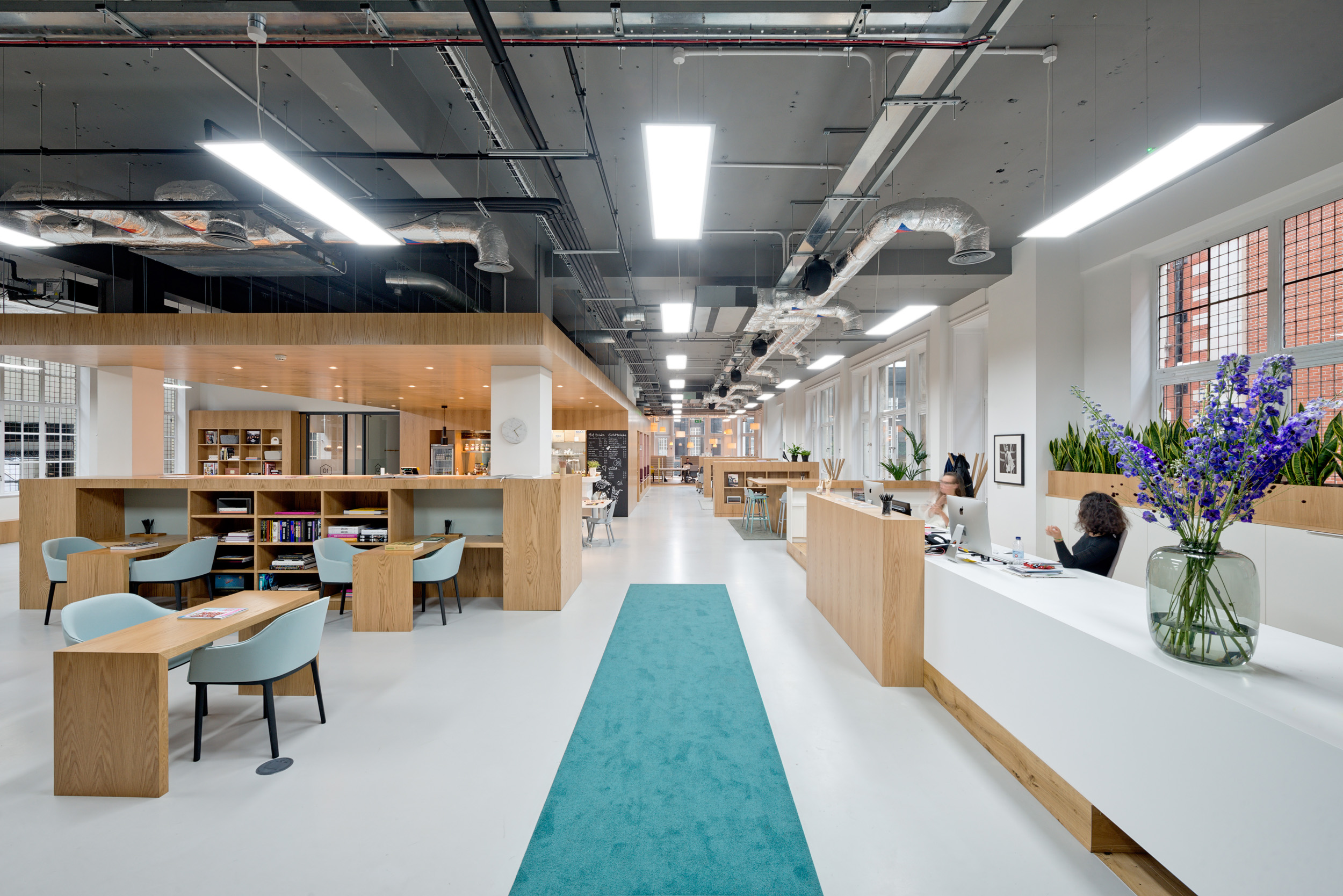 Spacious open-plan workspace with wood furnishings and a blue carpet runner at Spaces reception, Oxford Street.