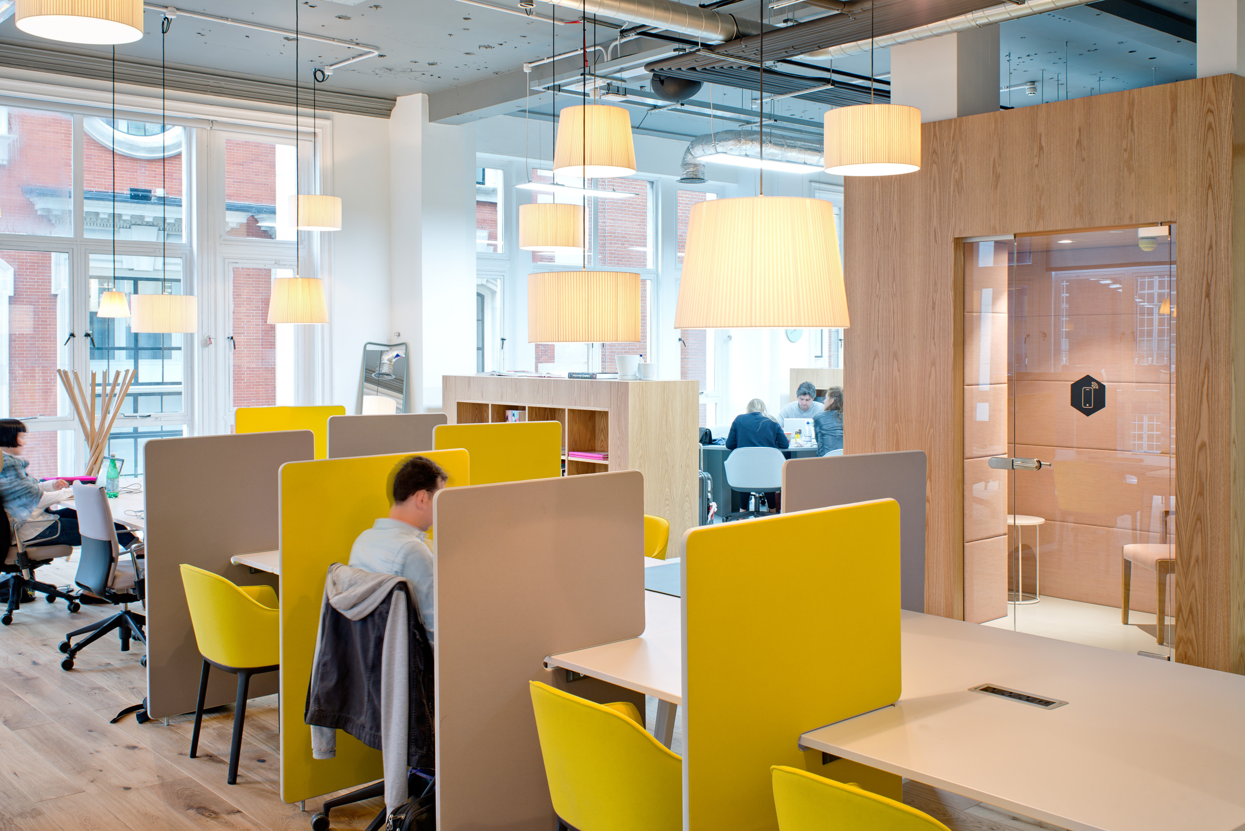 Additional workstations with yellow accents and pendant lights offer ample seating and workspace in the open area at Spaces, Oxford Street.