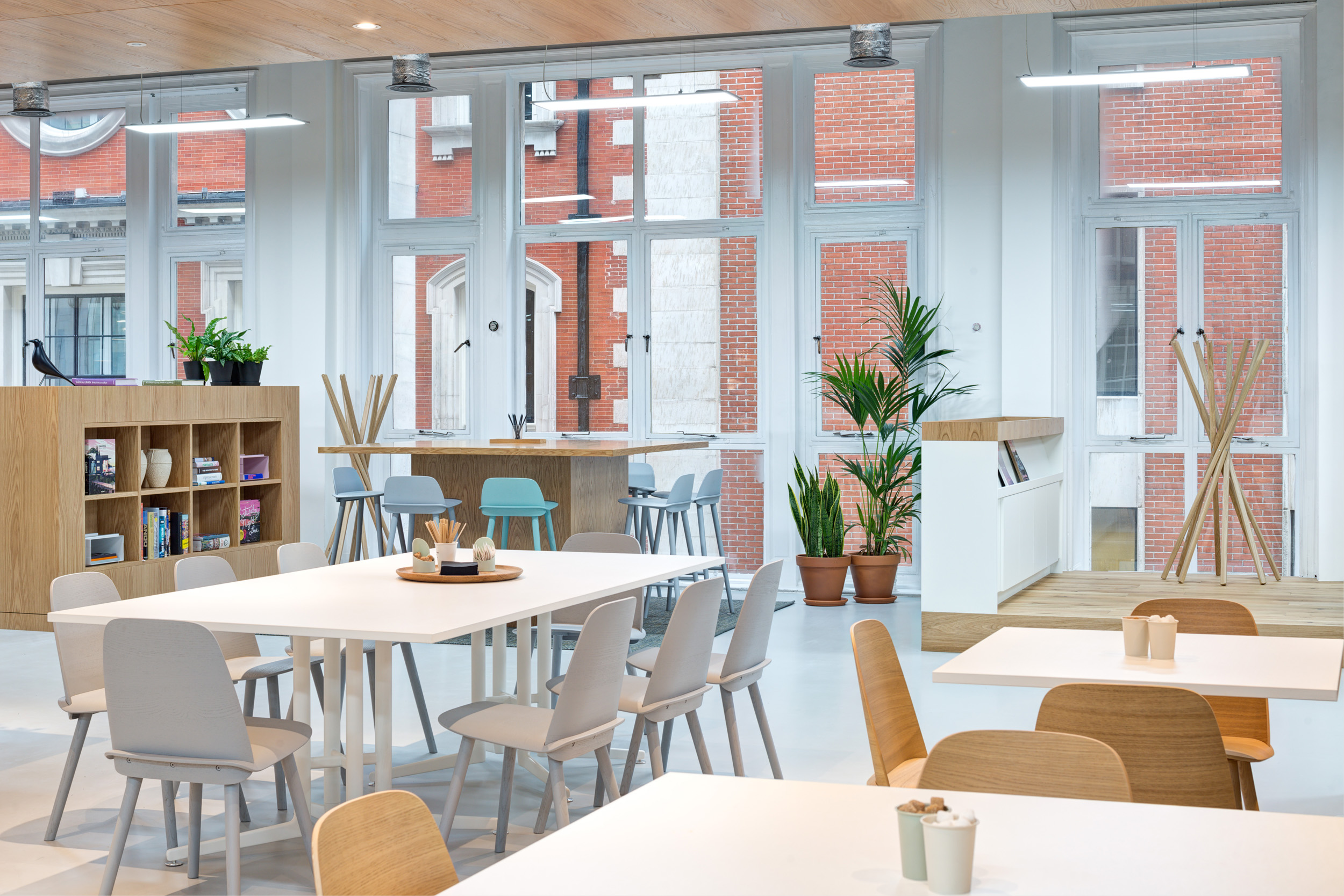 Breakout area with white tables and high stools, located near large windows at Spaces, Oxford Street