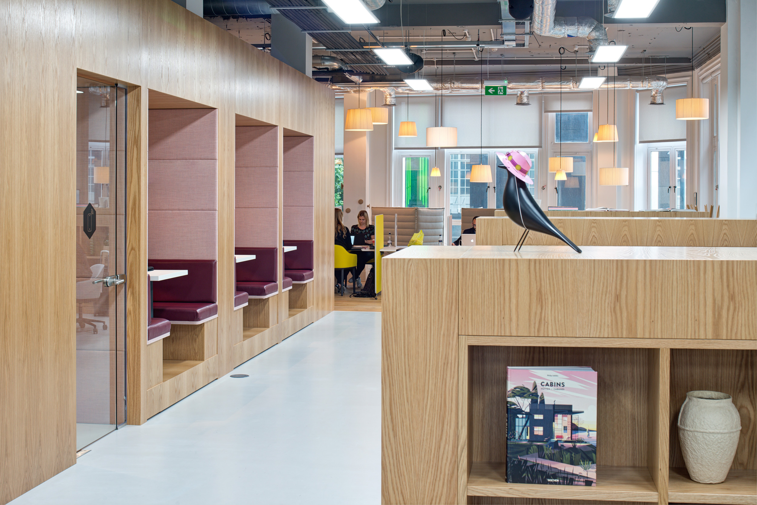 Private booths with pink cushioned seating and wooden panelling in Spaces, Oxford Street.