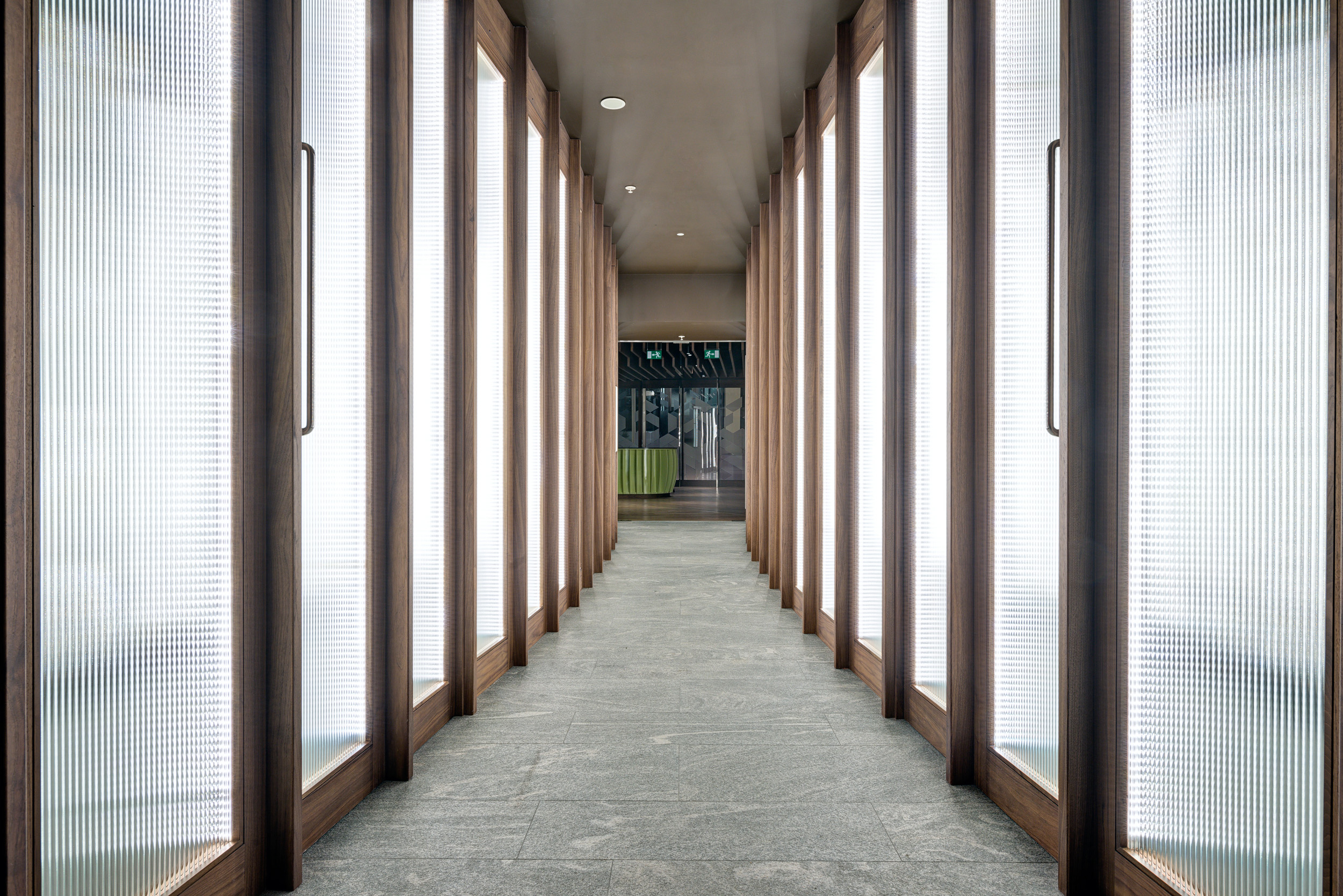 Backlit hallway leading to private offices at The Office Group's workspace in The Shard, combining modern design with natural materials.
