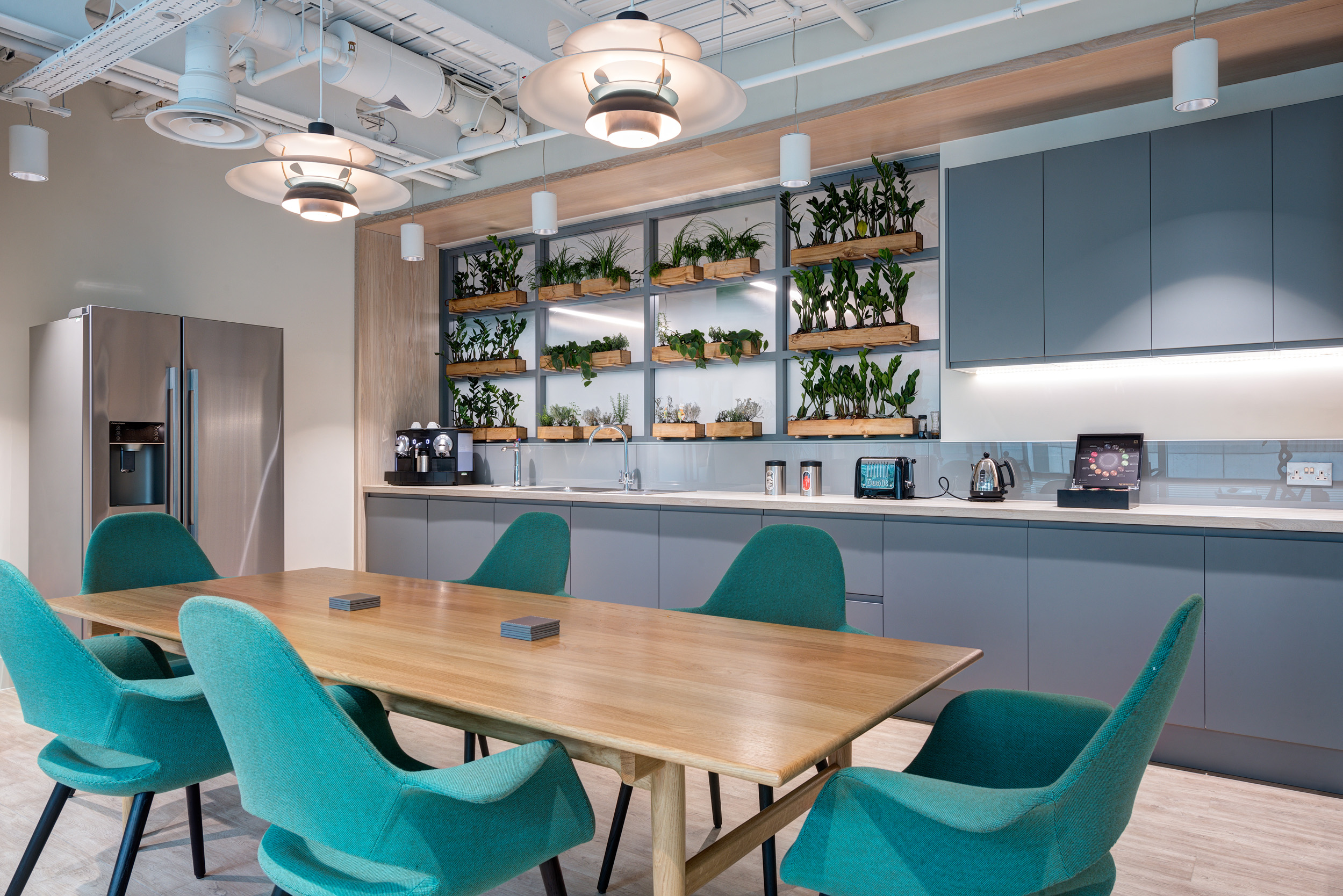 Vitruvian Partners teapoint area and dining area at Vitruvian Partners' office, with biophilic design elements and sleek furniture, providing a relaxing environment for employees.