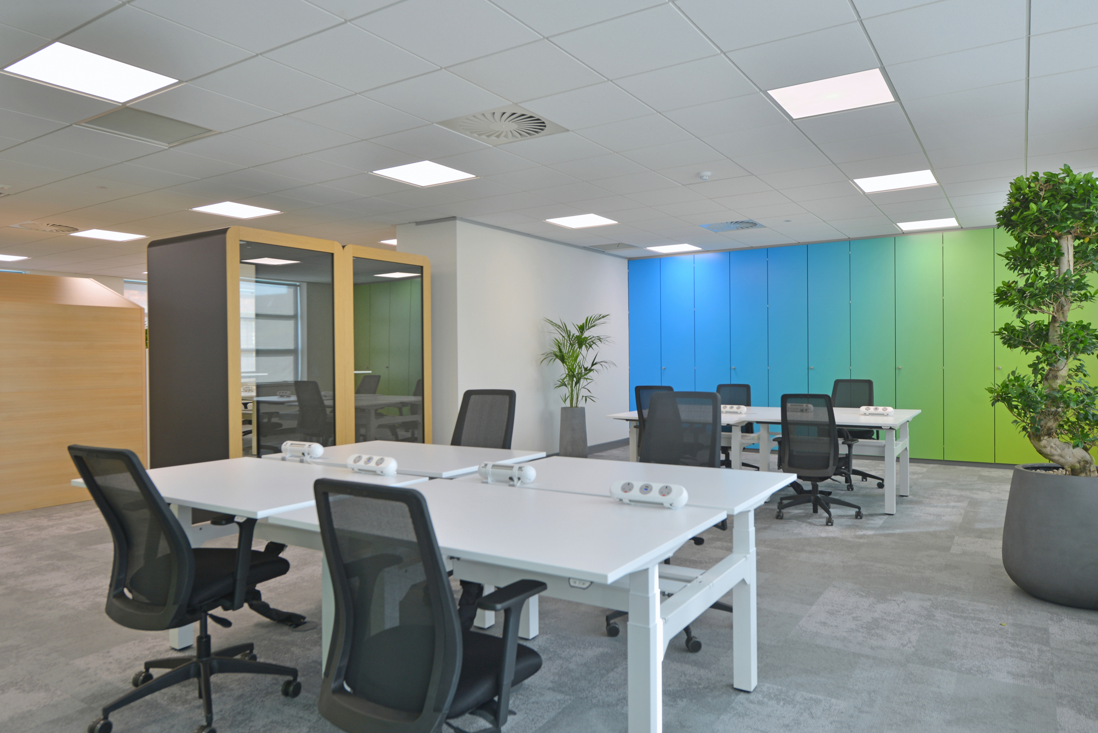 Warrington spacious open workspace at Fujitsu Services Warrington featuring ergonomic desks and vibrant blue and green storage units. Designed by Modus Workspace, this office promotes a bright and collaborative environment.