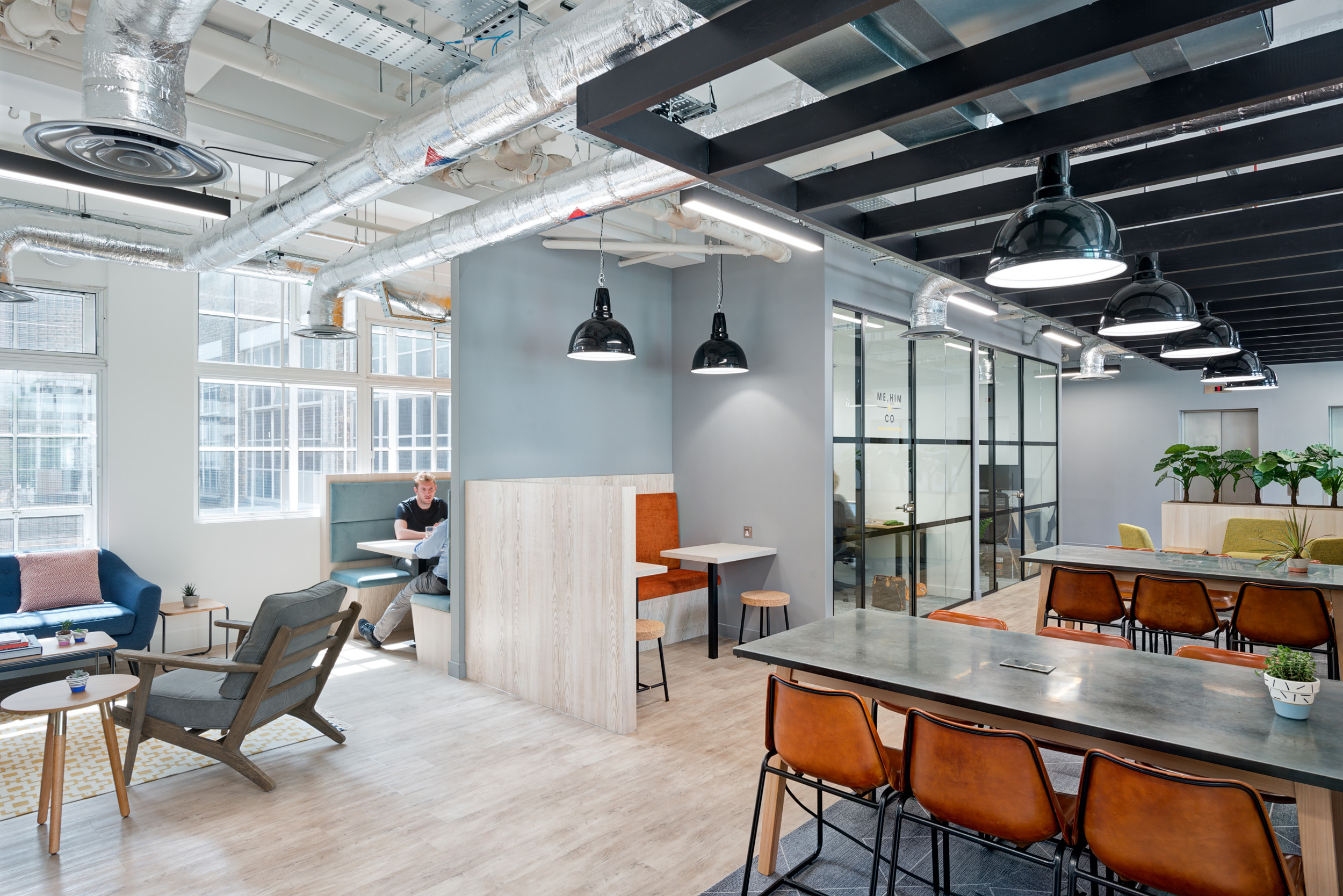 Worklife Clerkenwell open collaborative area designed by Modus Workspace, showcasing a mix of seating options including booths and lounge chairs under industrial lighting, ideal for informal meetings and relaxation.