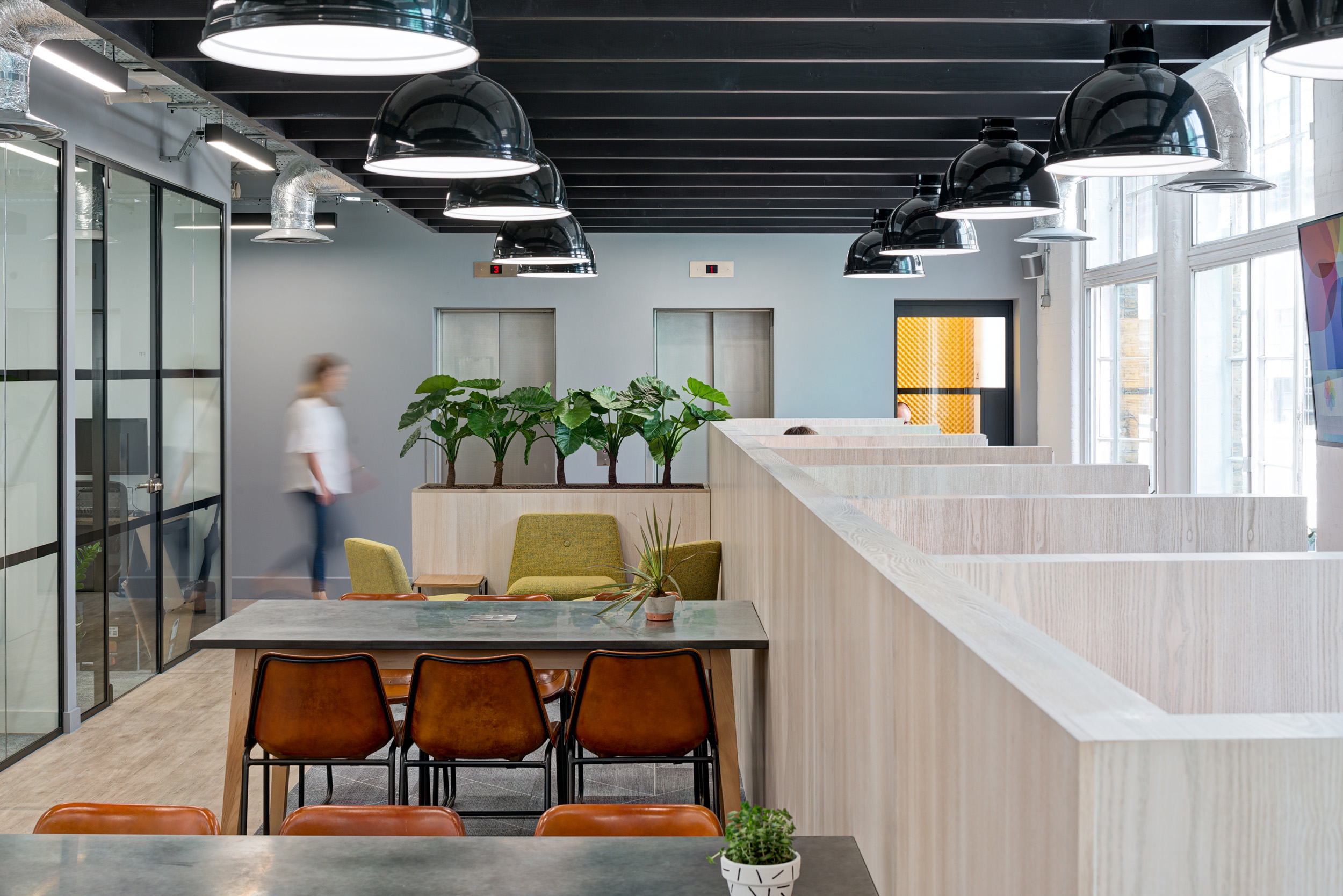 Worklife Clerkenwell open-plan workspace designed by Modus Workspace, featuring well-lit booths and modern workstations under exposed industrial-style piping and lighting.