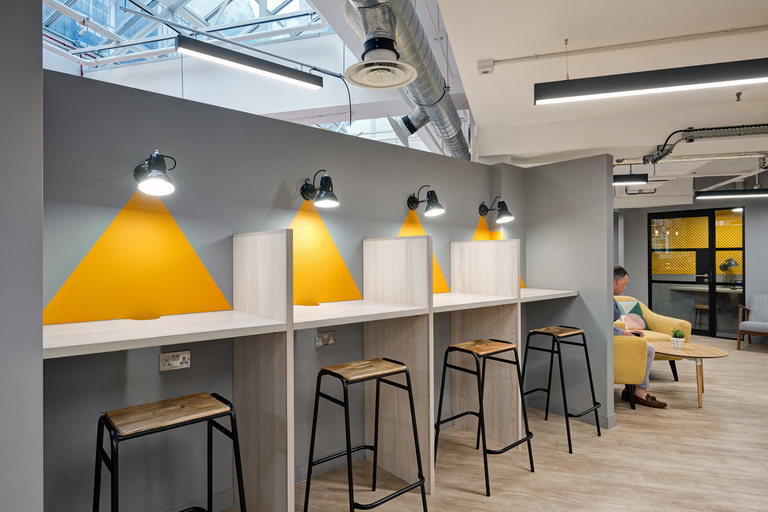 Worklife Clerkenwell quiet zone designed by Modus Workspace, featuring individual work pods with stylish task lighting against a vibrant yellow wall for focused work.