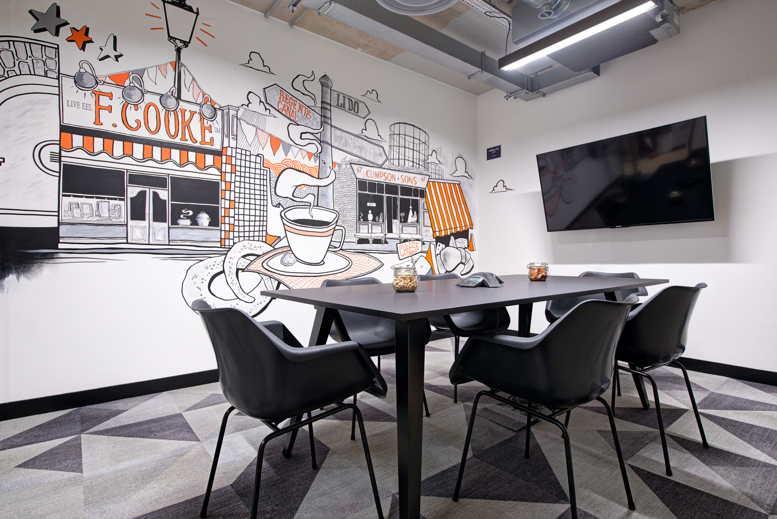 Worklife London Fields graphic meeting room, designed by Modus Workspace, with comfortable chairs and modern decor, providing a perfect spot for informal meetings or relaxation.
