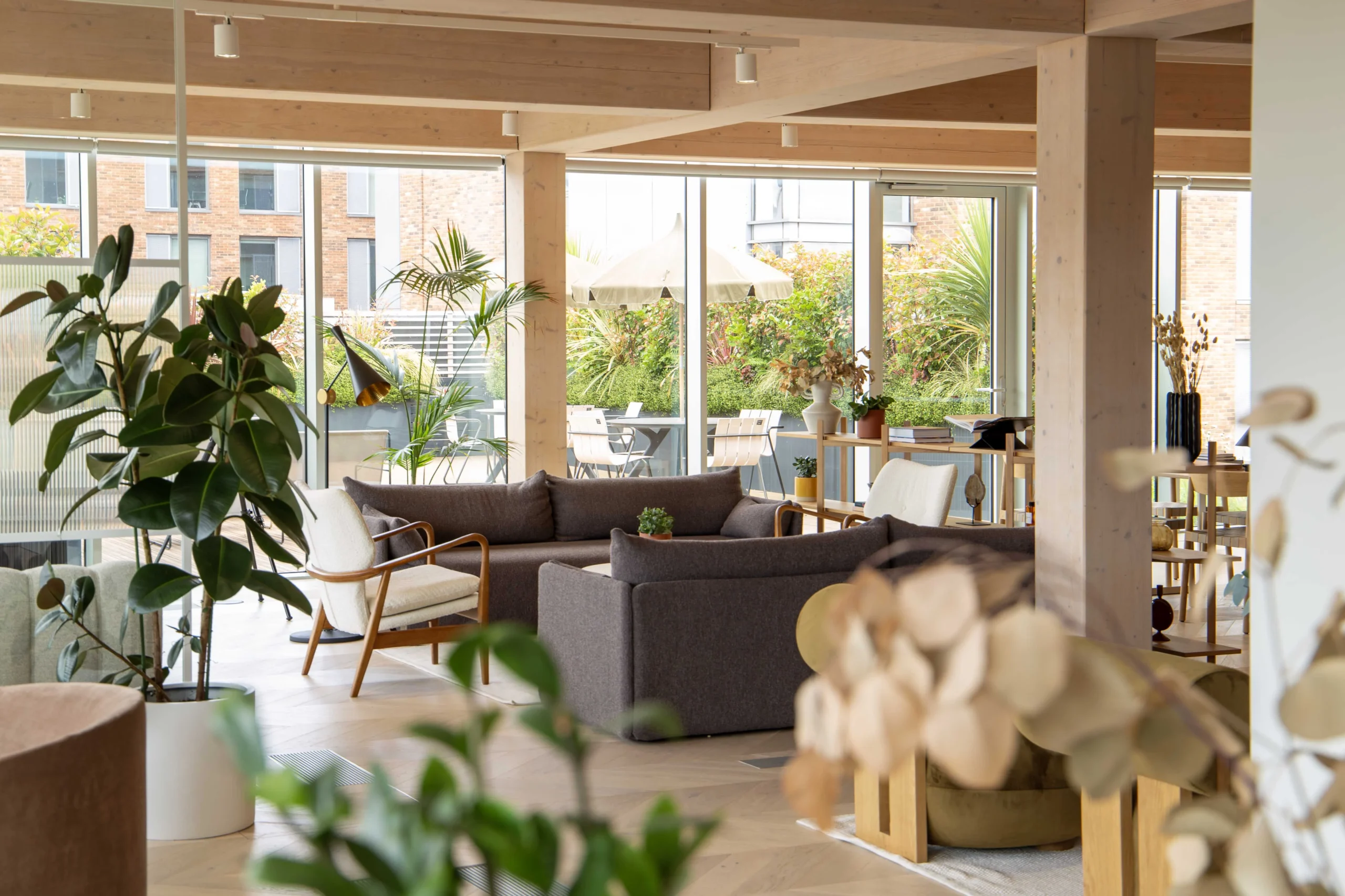 Techspace seating area with a biophilic view featuring large glass doors, soft seating and biophilic elements.