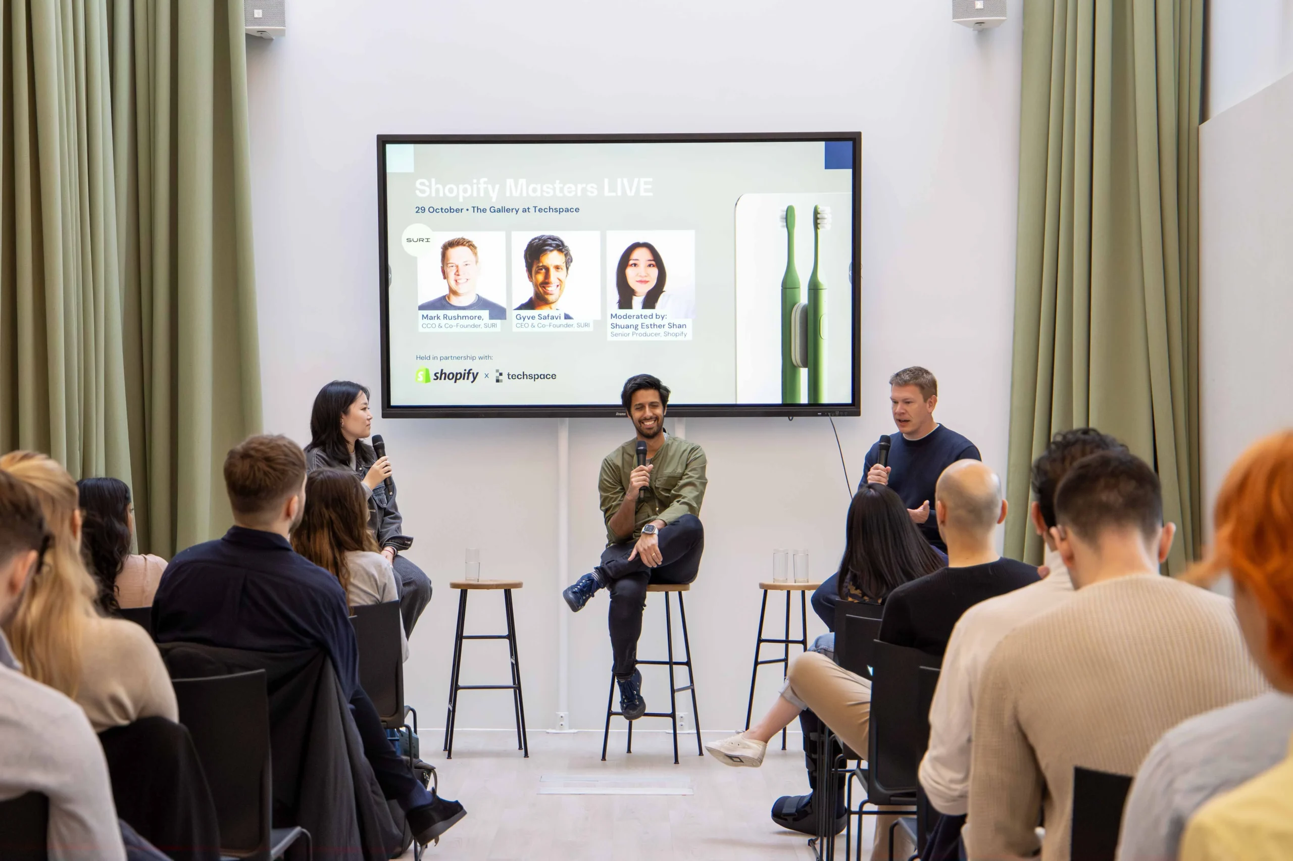 Techspace conference hall with employees featuring green curtains and a presentation being demonstrated