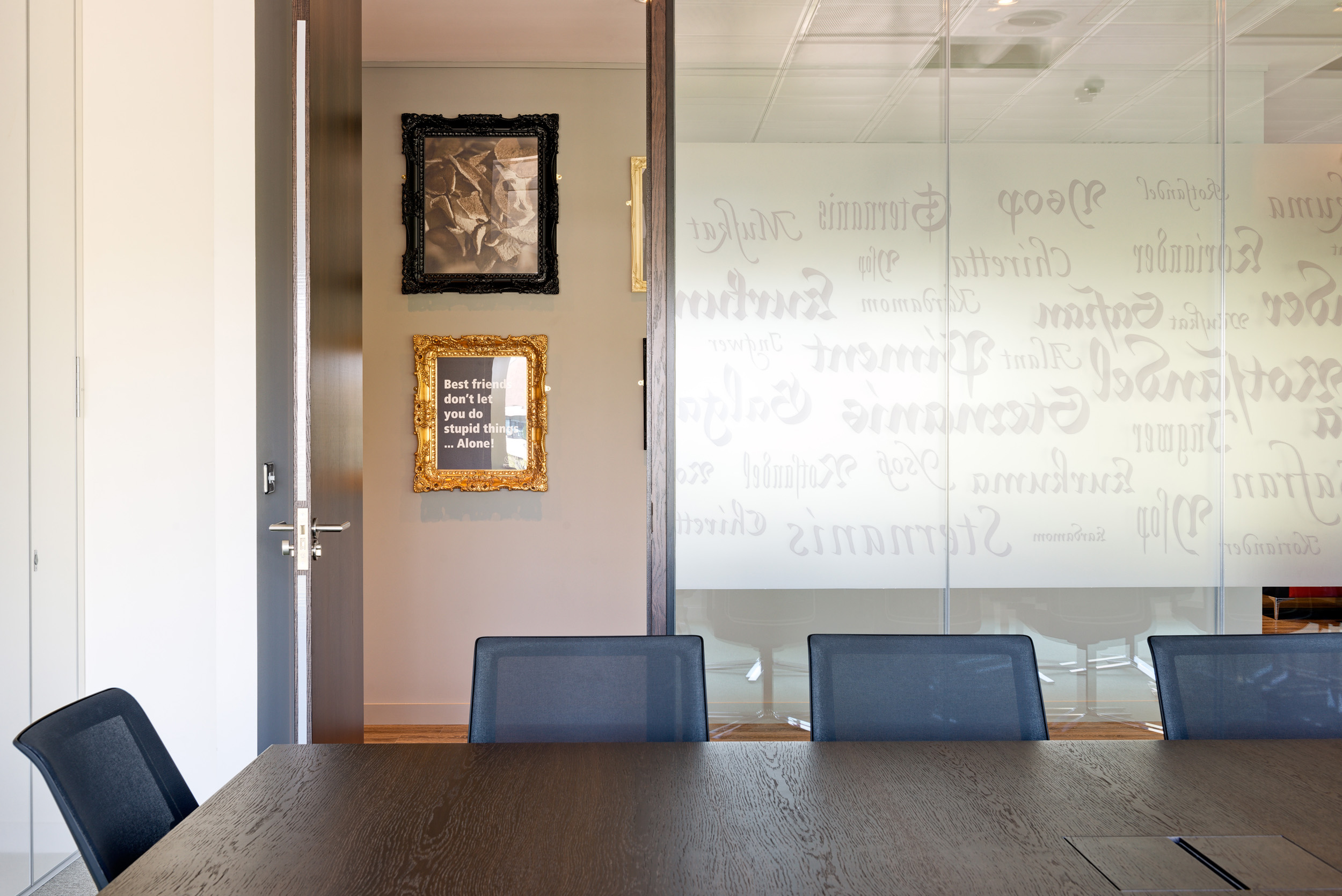 Jagermeister Meeting Room partitioned, glass, frosted wall with grey seats, a dark oak table and hanging images.