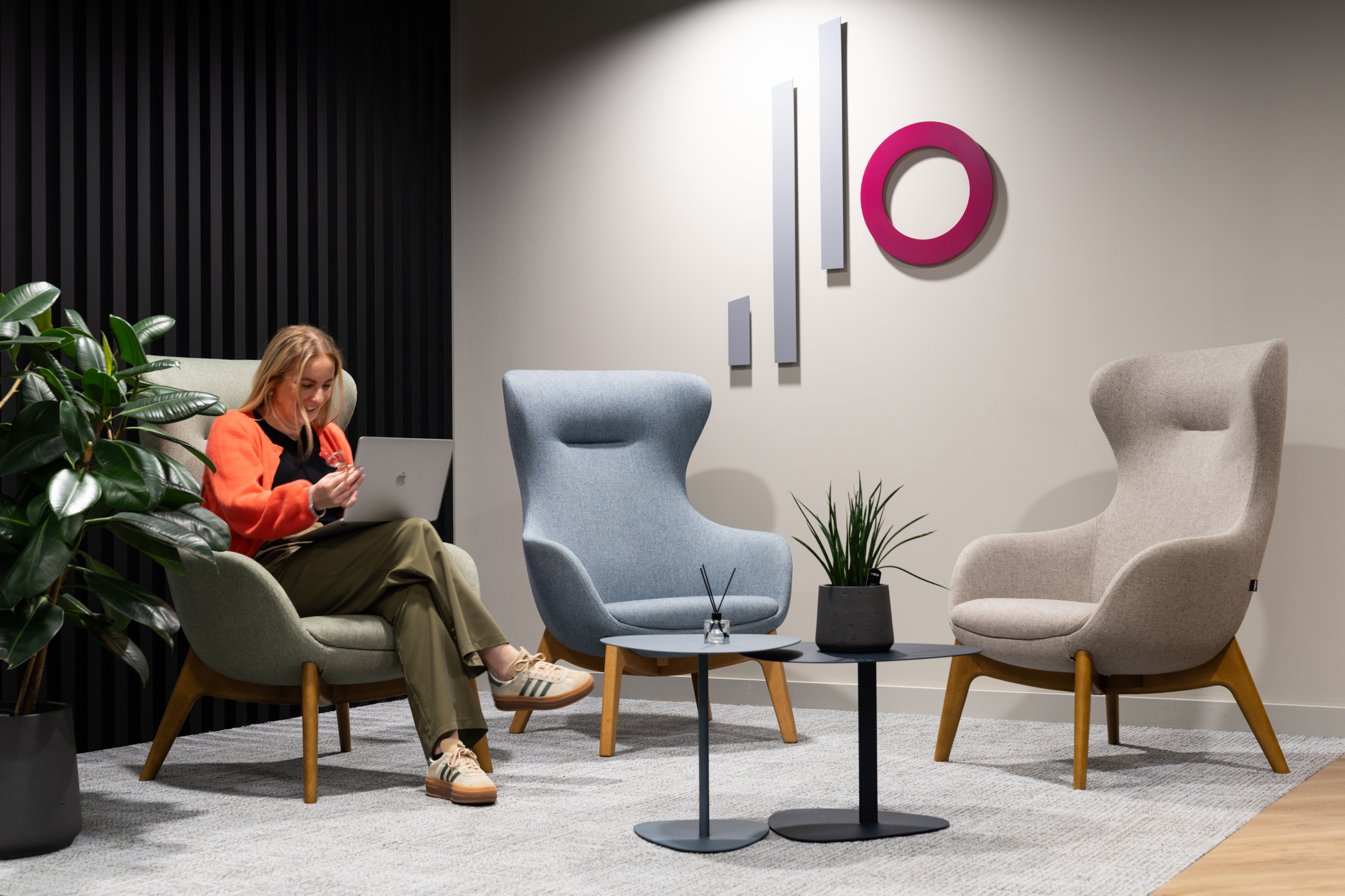 Costello Medical reception seating area with a branded logo on the wall, biophilic plants, and soft seating areas.