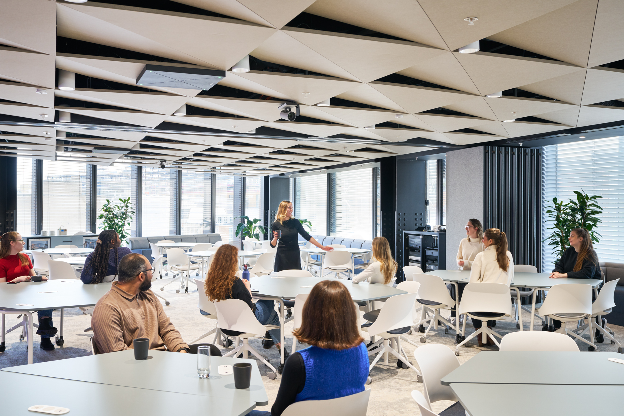 Entertainment Company desking area, with hexagon tables, white chairs and an acoustic panelled ceiling.