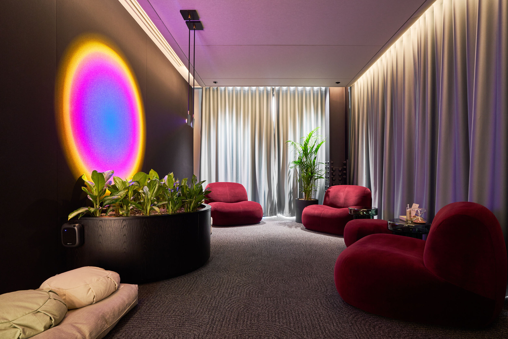 International Technology and Data Firm relaxation zone, with soft purple finishes, soft seating, ceiling-to-floor curtains, and a plotted plant.