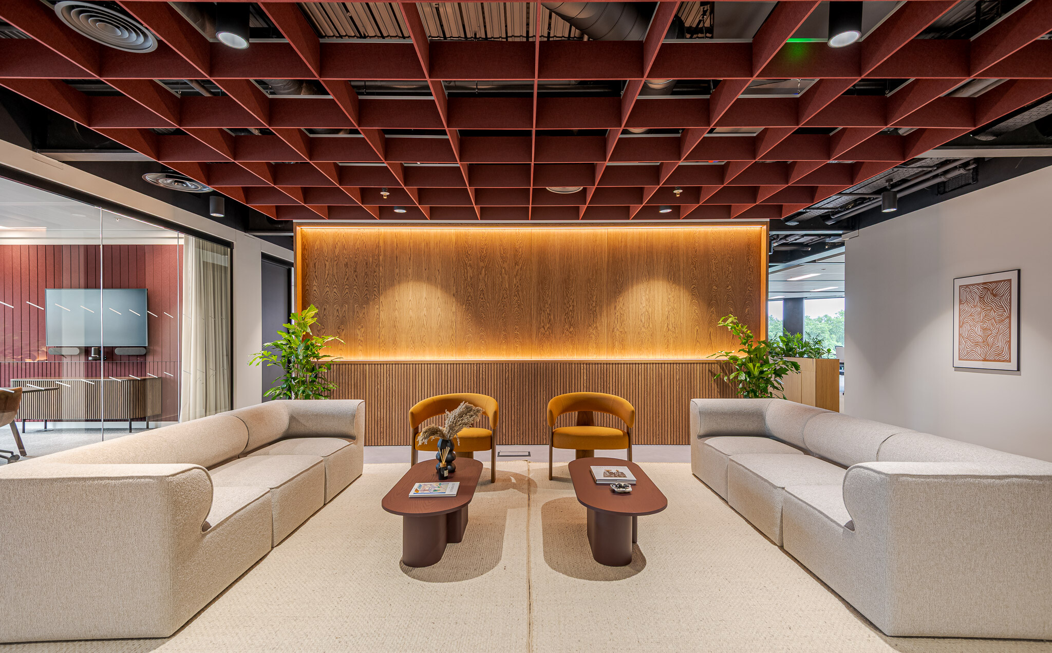 Arbor Level 4 Tenant-Ready™ reception designed by Modus, showcasing twin taupe sofas, ochre armchairs, timber wall panelling with ambient lighting, and a red acoustic ceiling grid.
