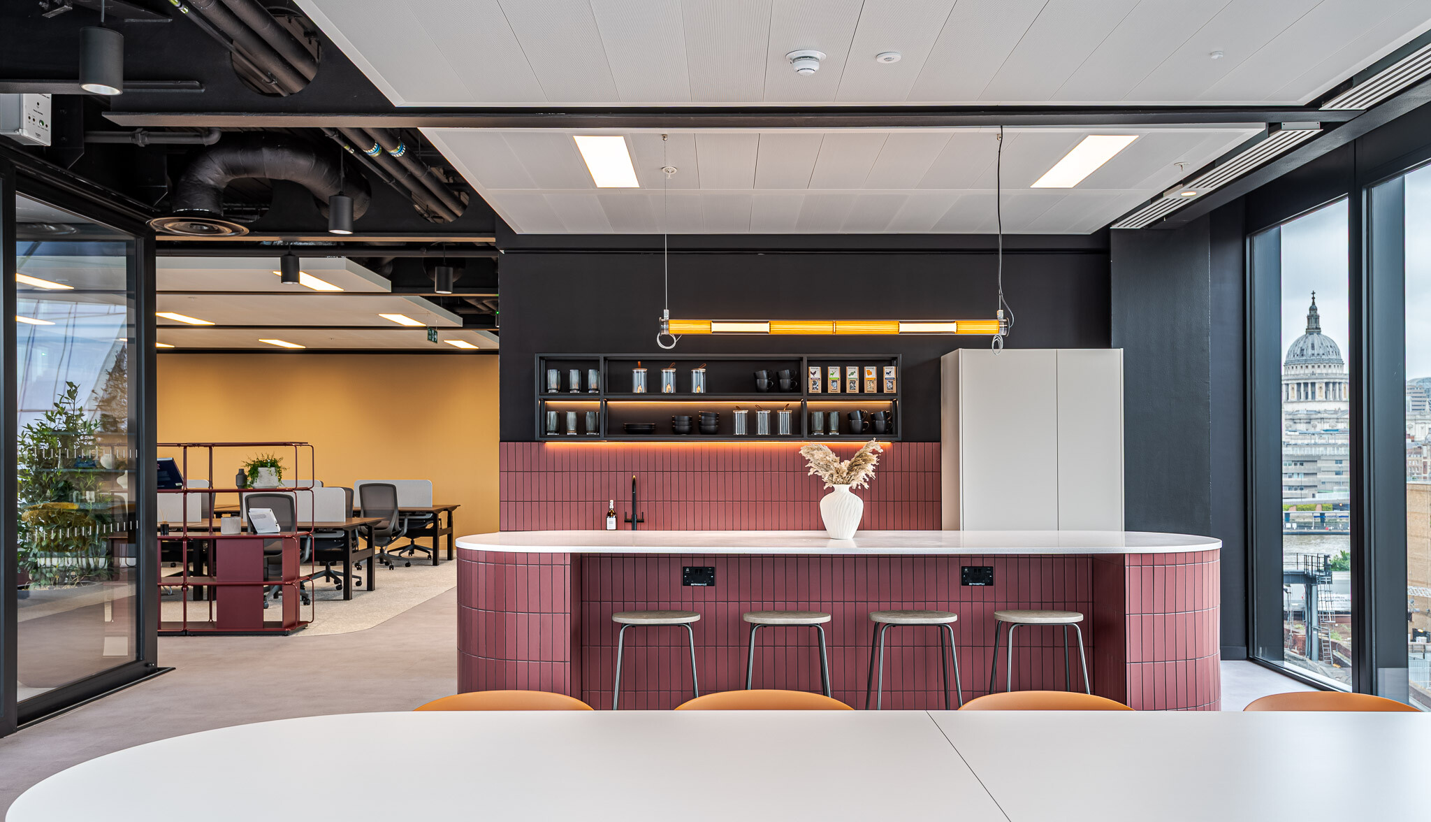 Tenant-Ready™ teapoint at Arbor Level 4, designed by Modus, featuring a curved island clad in red vertical tiles, open shelving with black crockery, and panoramic views over London including St Paul’s Cathedral.
