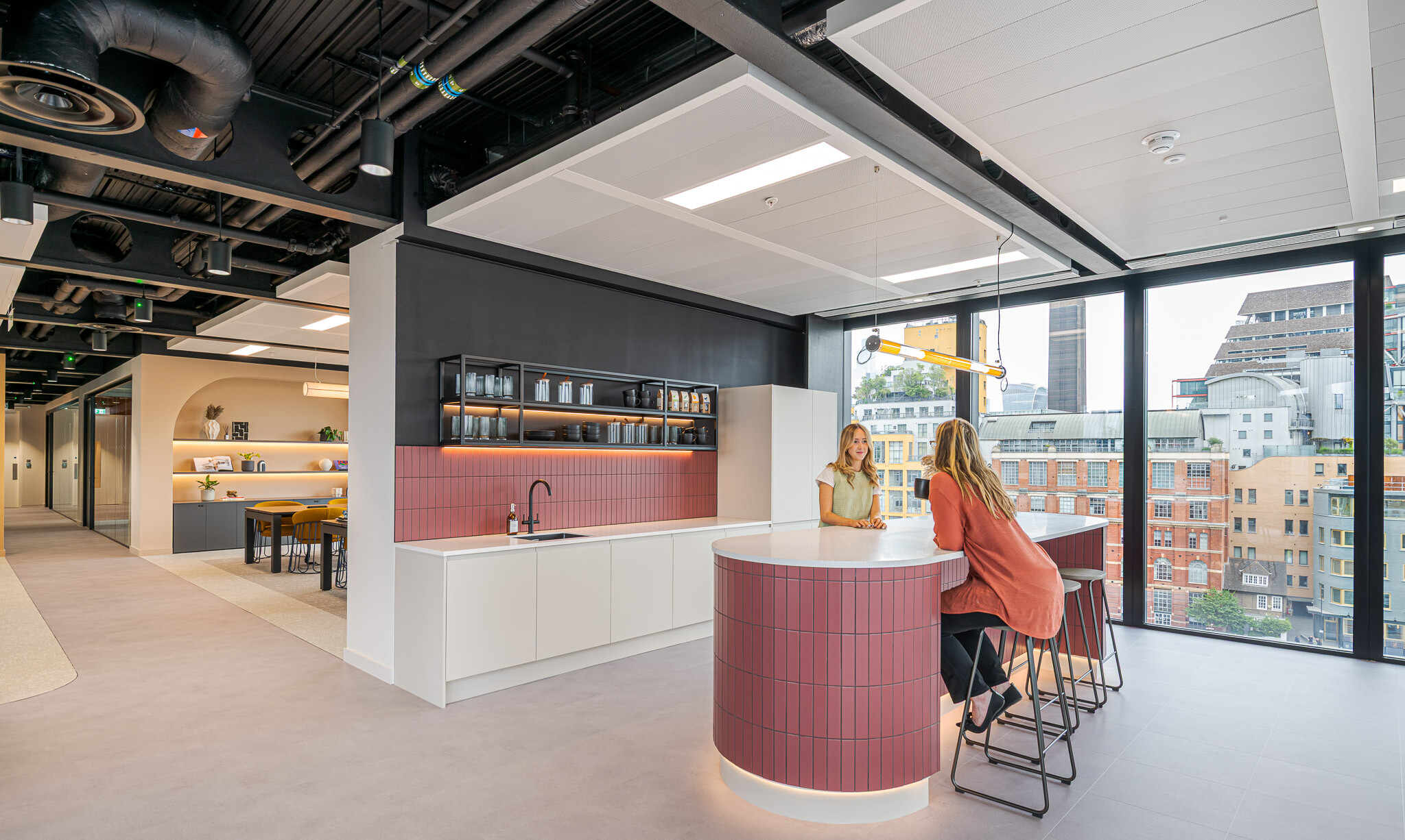 Tenant-Ready™ teapoint at Arbor Level 4, designed by Modus, with curved red-tiled island, open shelving, soft lighting, and full-height glazing offering views across London’s architectural skyline.
