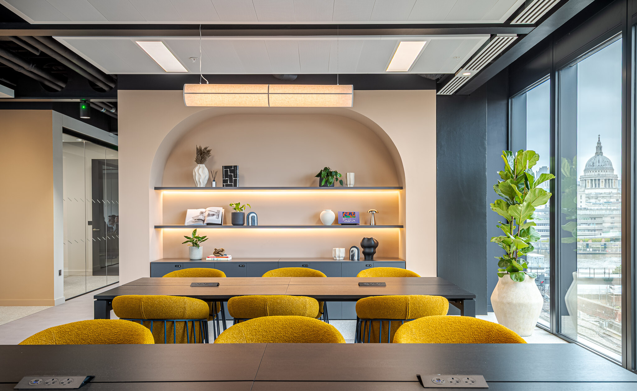 Stylish shelving alcove in the Arbor Level 4 Tenant-Ready™ workspace by Modus, with integrated lighting, decorative objects and a backdrop of mustard chairs and black worktables overlooking St Paul’s Cathedral.