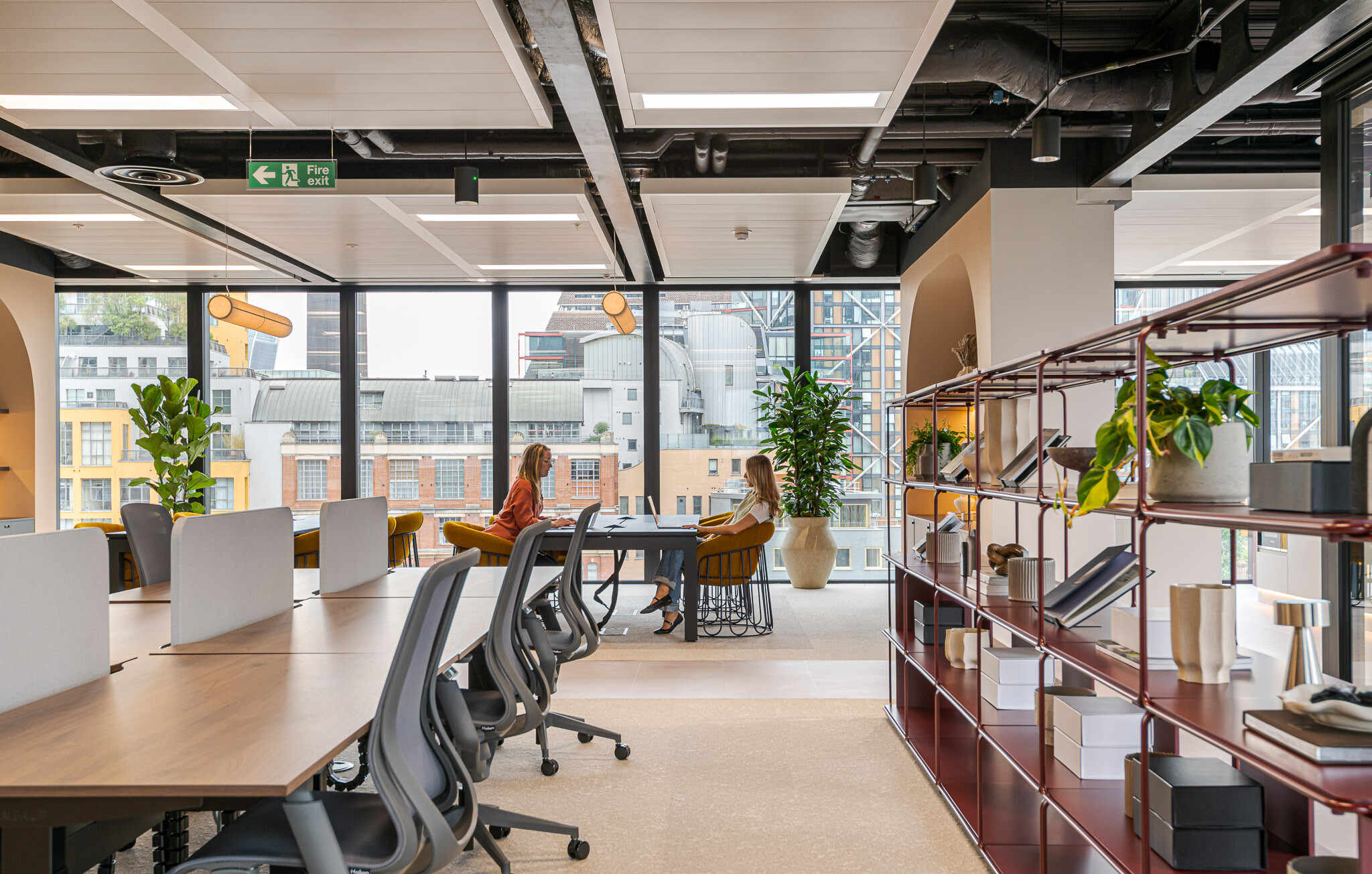Collaborative workspace at Arbor Level 4, part of Modus’s Tenant-Ready™ design, featuring shared desks, mustard chairs, decorative burgundy shelving and full-height glazing with views of central London.