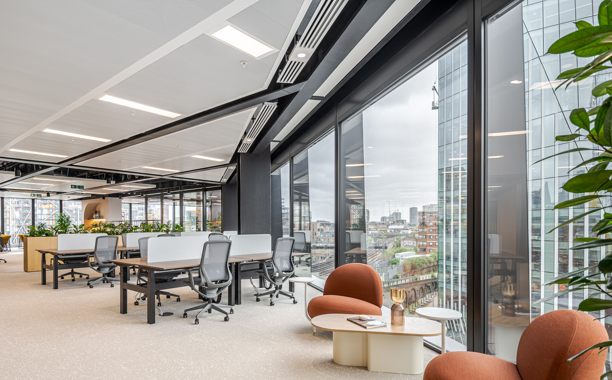 Workspace at Arbor Level 4 Tenant-Ready™ fit out by Modus, with rows of desks, planter dividers, and a soft seating corner positioned beside floor-to-ceiling windows offering city skyline views.
