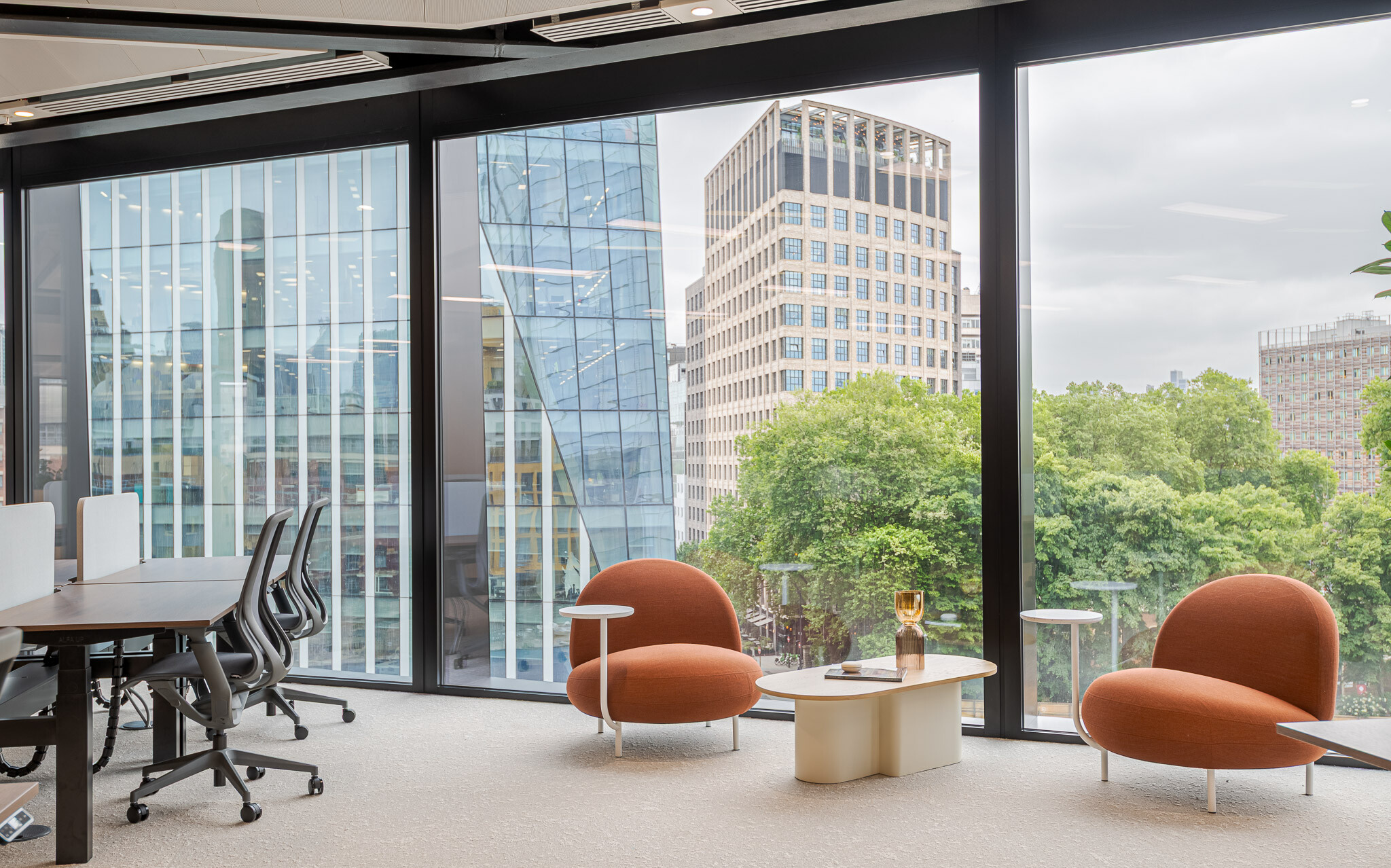 Window-side lounge area at Arbor Level 4, part of Modus’s Tenant-Ready™ fit out, with two sculptural terracotta chairs, soft coffee tables and panoramic views of London’s modern architecture and greenery.