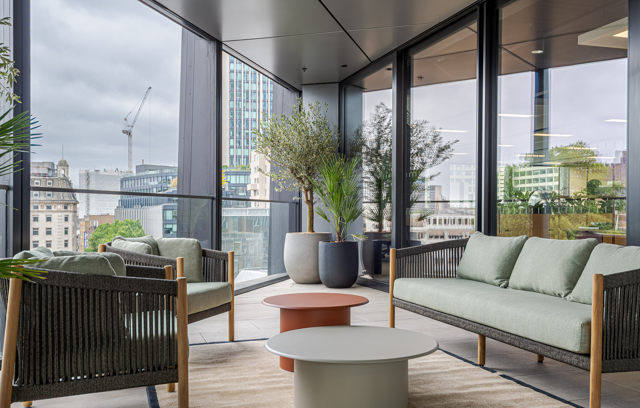 Outdoor terrace at Arbor Level 4, designed by Modus as part of the Tenant-Ready™ scheme, with lounge seating, round coffee tables, and potted trees set against a backdrop of London’s skyline.