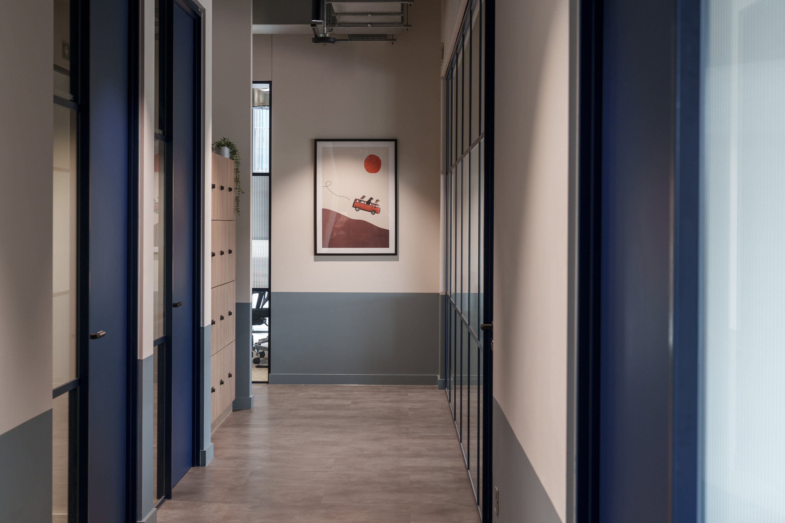 Hallway at Newflex One Station Hill with blue-framed glass doors, built-in lockers, and modern artwork at the end wall.