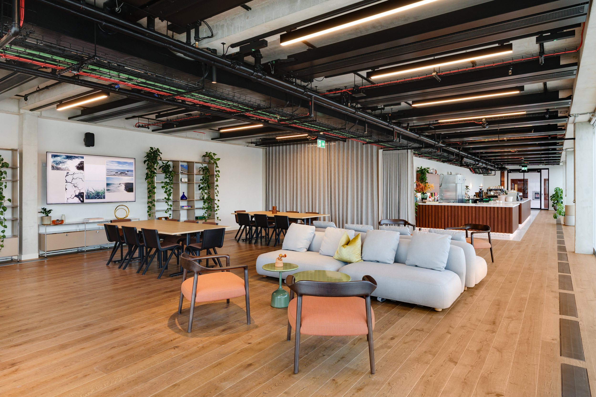 Modus designed the Space House Clubhouse with an open layout combining lounge seating, communal tables, and a walnut bar, framed by exposed ceilings and soft lighting.